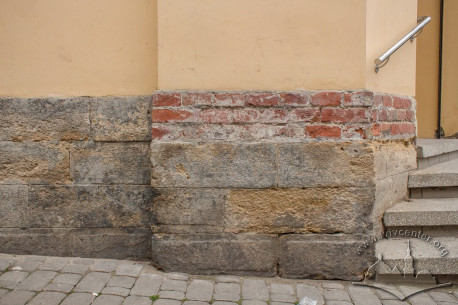 Vul. Lysenka, 2. Lower part of the facade: it is visible that the wall itself is made of bricks, and it is only faced with white stone